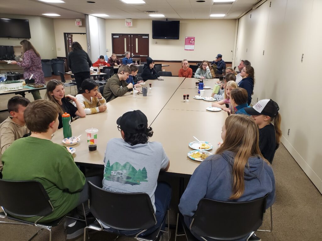 Students sitting at a table during a Sigma Lambda Chi meeting.